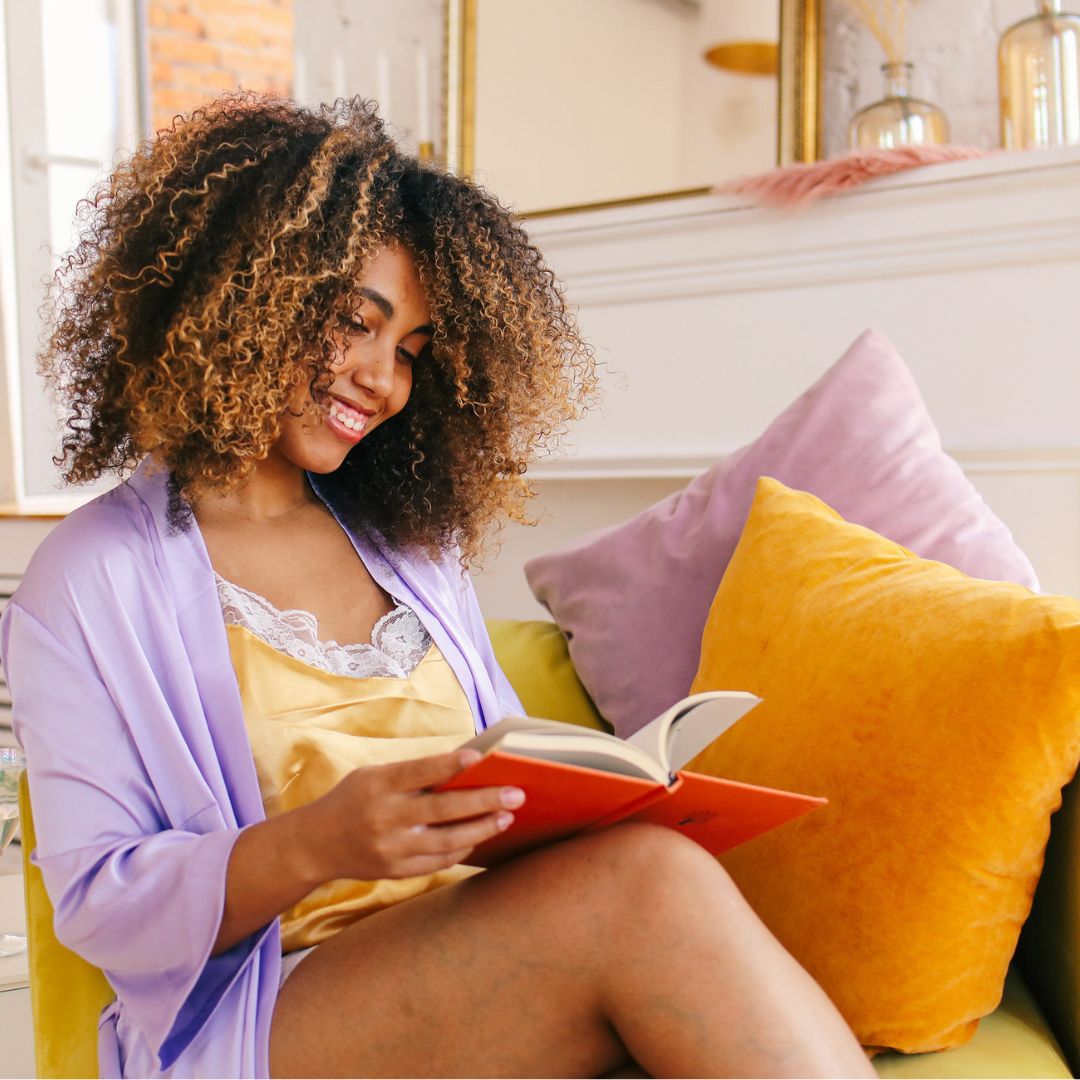 woman reading book, relaxing in her apartment