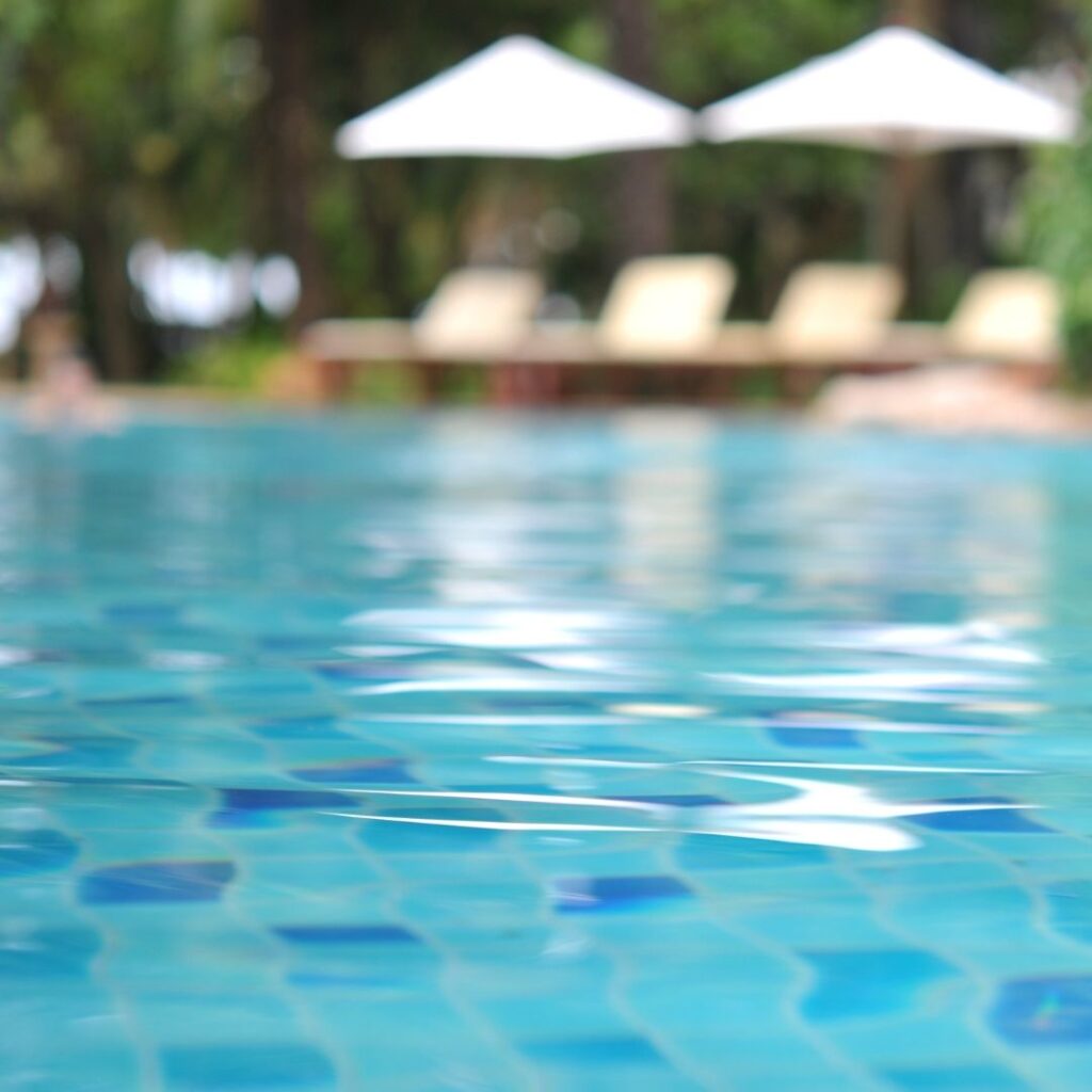 A vibrant, sunlit swimming pool with adjacent hot tub and comfortable lounge chairs in a residential community.
