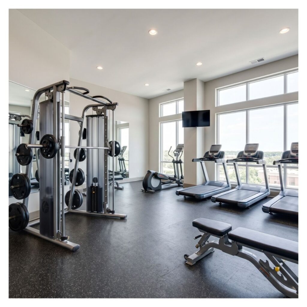 A clean, modern apartment community fitness center featuring advanced weight machines, treadmills, and large windows with abundant natural light.